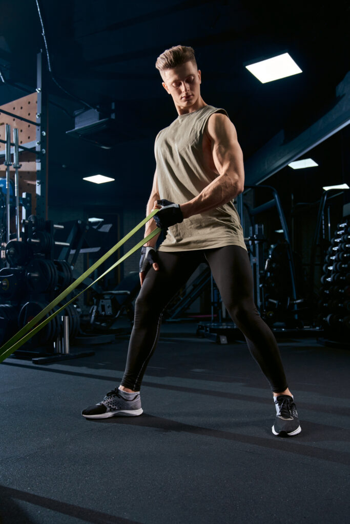 Muscular man training back with resistance band.