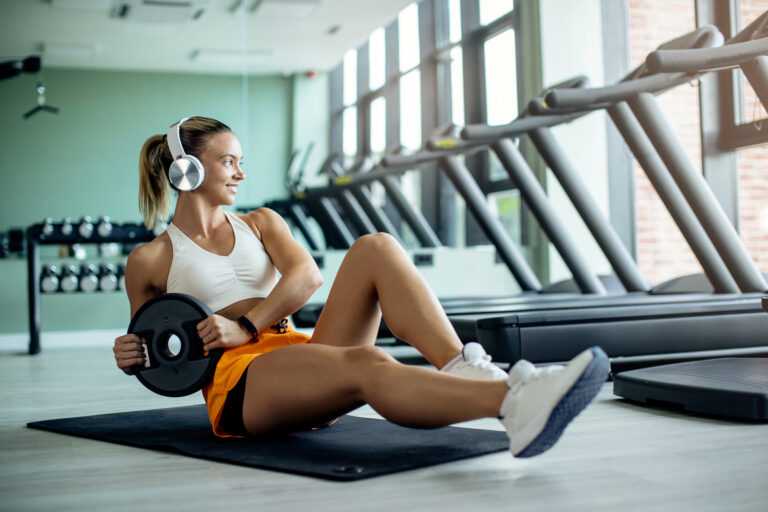 Young female athlete doing abdominal exercises with weight plate
